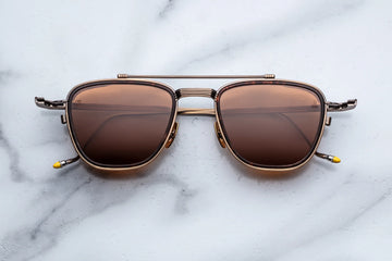 Antique gold metal aviator frame with brown lenses on a white marble background
