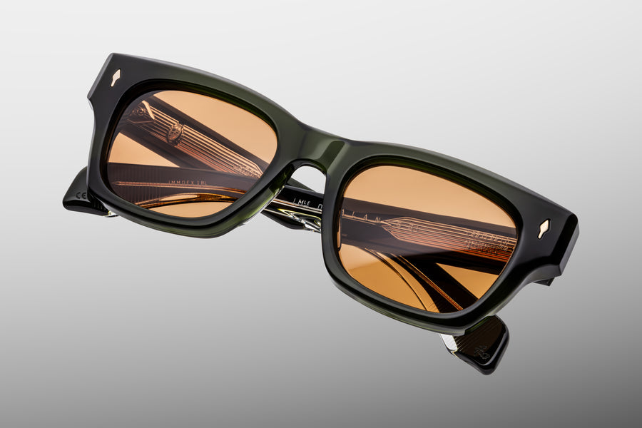 Green acetate sunglasses with orange lenses and ornate silver wirecore against a grey background