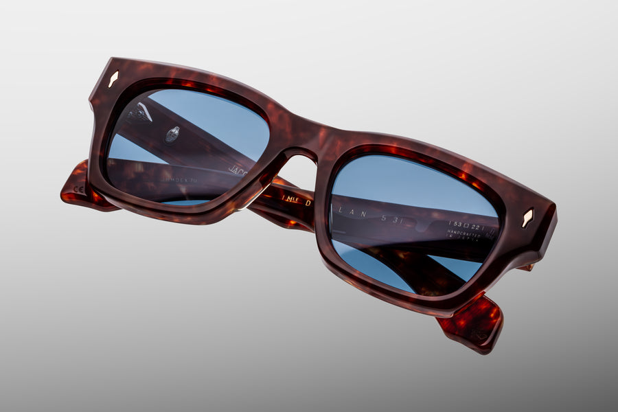 Reddish brown tortoiseshell acetate sunglasses with blue lenses against a grey background