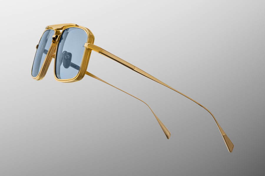 Side profile of a gold metal aviator frame, with thin golden temples, on top of a grey background.
