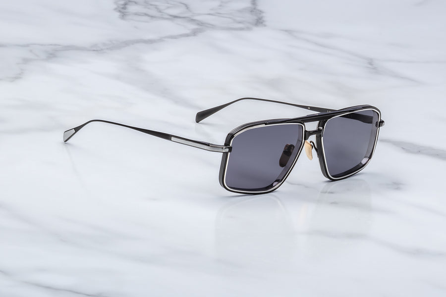 Metal sunglasses with black frames and dark grey lenses on a marble surface.