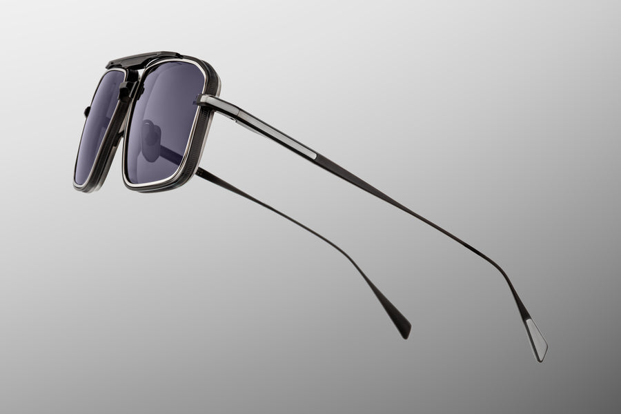 Profile view of a black metal sunglass frame with silver accents, thin temples with a silver tailfin.