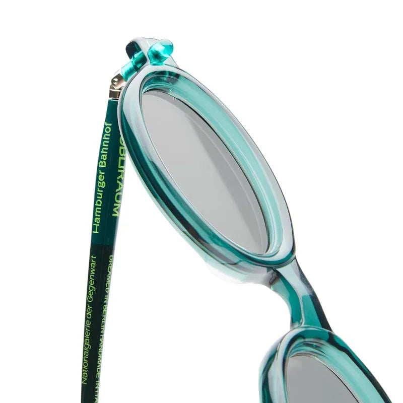 Teal oval sunglasses with a close-up on the lens and frame details.