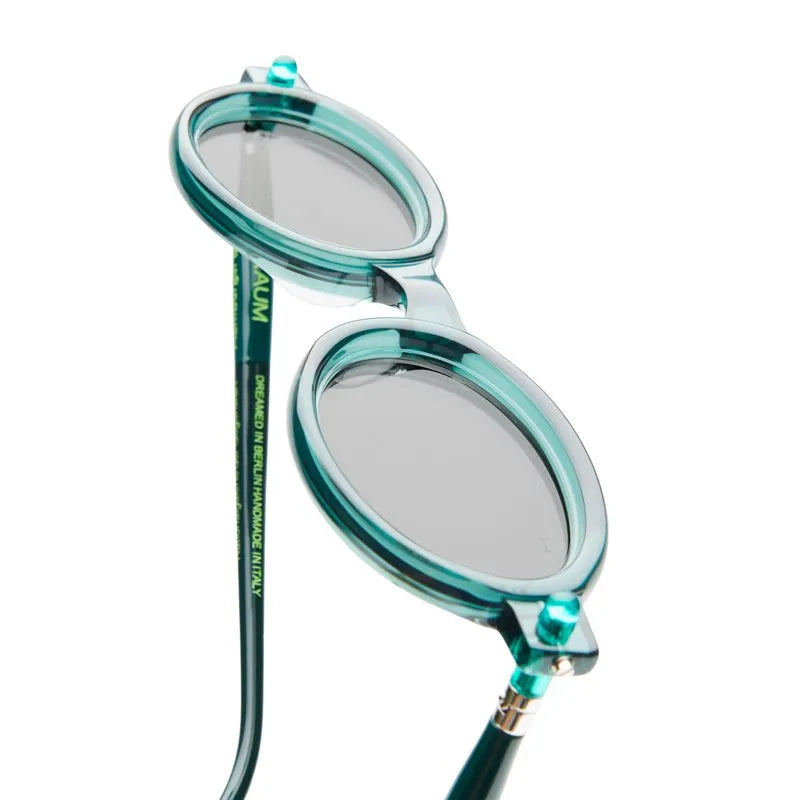 Teal oval sunglasses with a close-up on the lens and frame details.