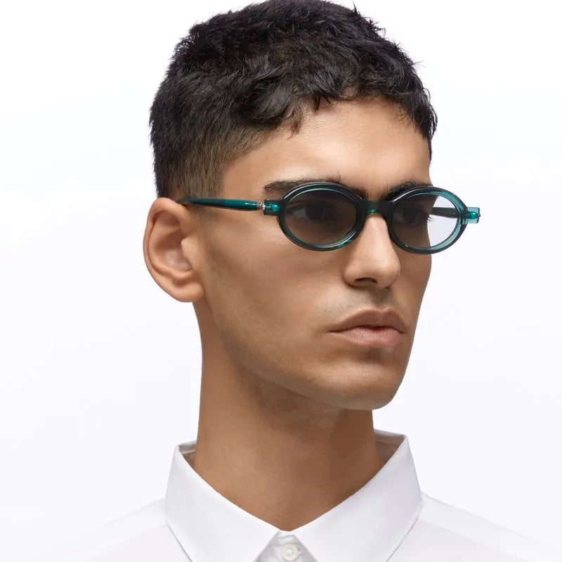 Man in profile view wearing a white shirt and green sunglasses on a white background