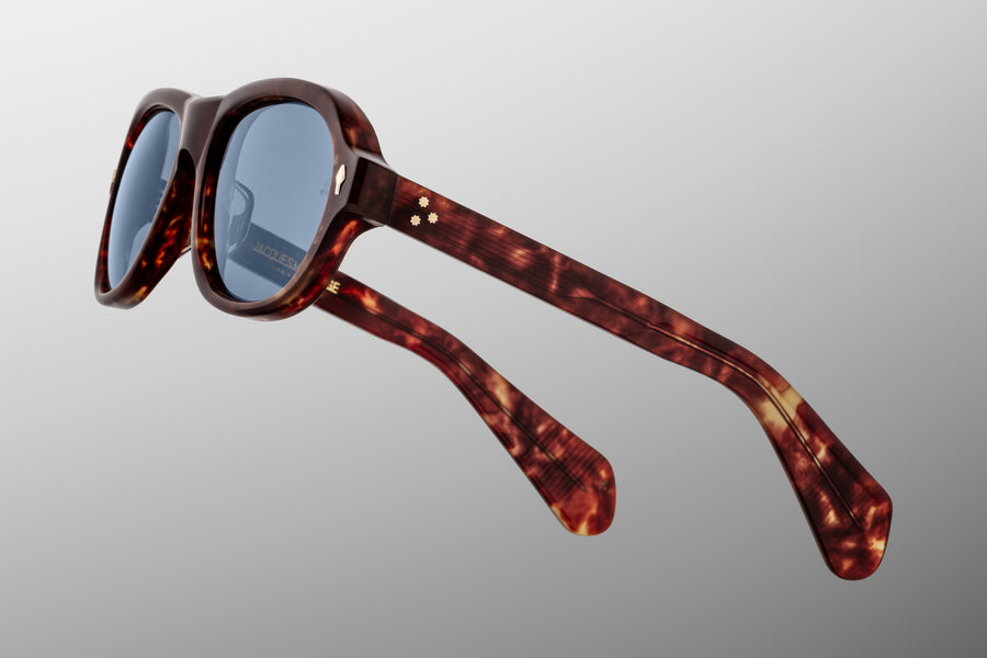 Side profile of round aviator style sunglass frames, in a brown tortoiseshell acetate and blue lenses, with gold hardware.