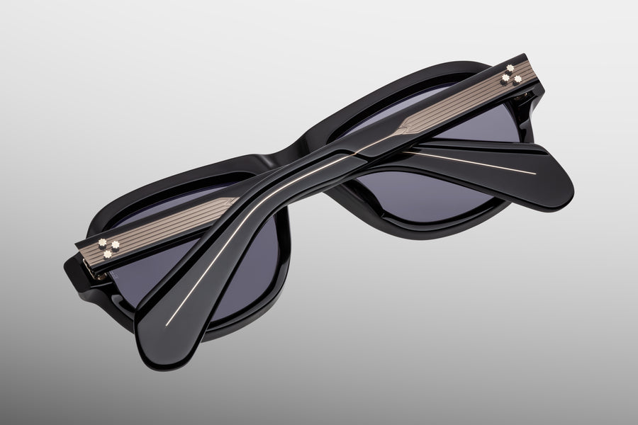 Back view of a black acetate aviator sunglass, with temples folded over one another, highlighting the gunmetal wirecore hardware.