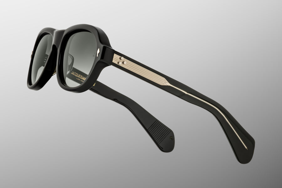 Side profile of round aviator style sunglass frames, in green toned black acetate and green gradient lenses, with gold hardware.