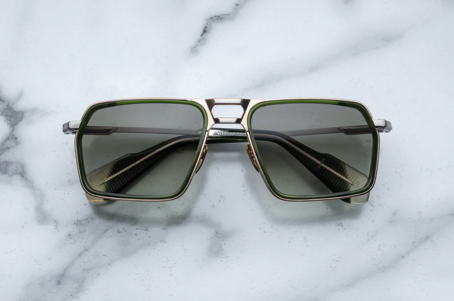 Sunglasses with gold frame and dark lenses on a marble surface