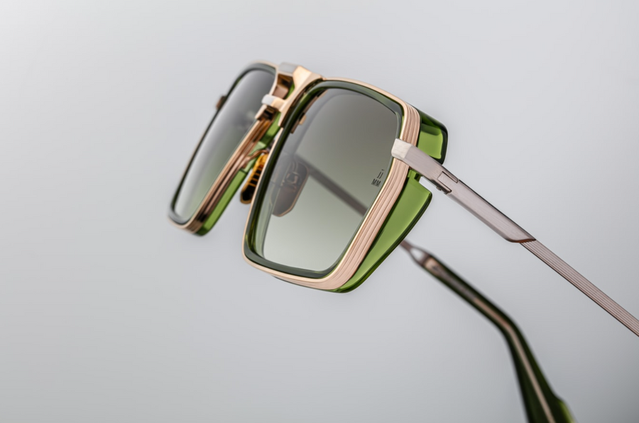 Sunglasses with gold frame and green lenses on a light gray background