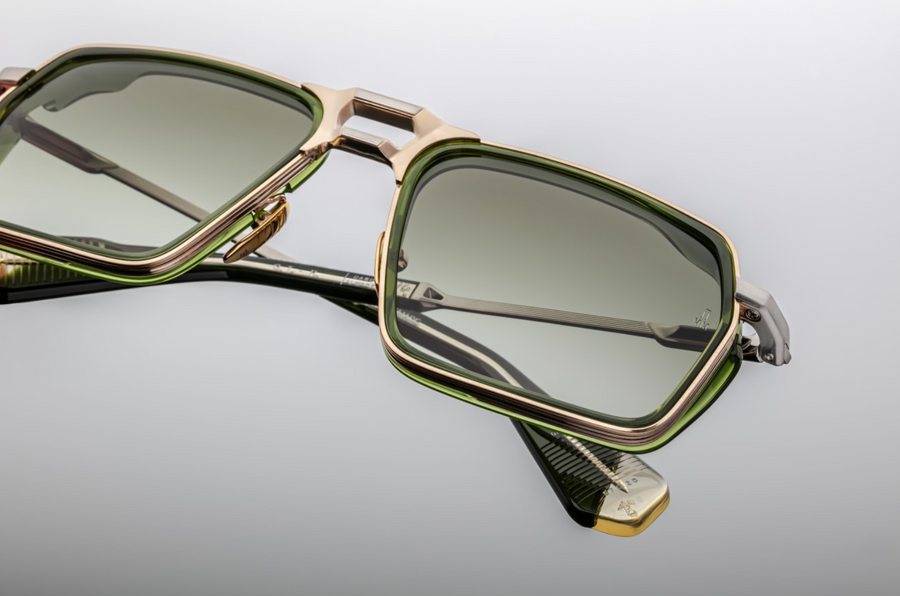 Sunglasses with gold frame and green lenses on a reflective surface