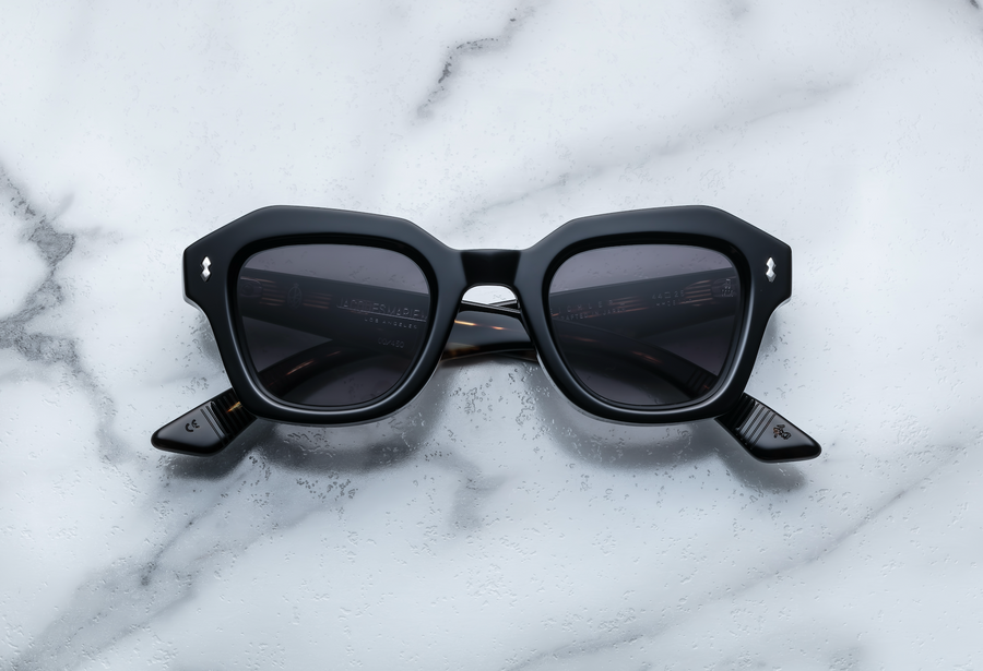 Black square sunglasses with silver hardware, front facing on a white marble background
