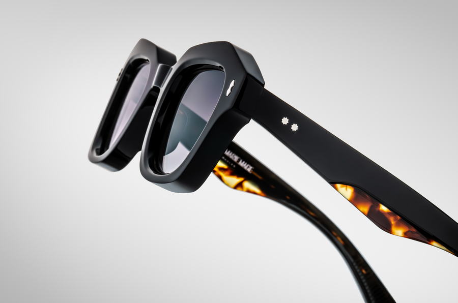 Close up of a profile view of black sunglasses, with tortoiseshell accents on the temples.