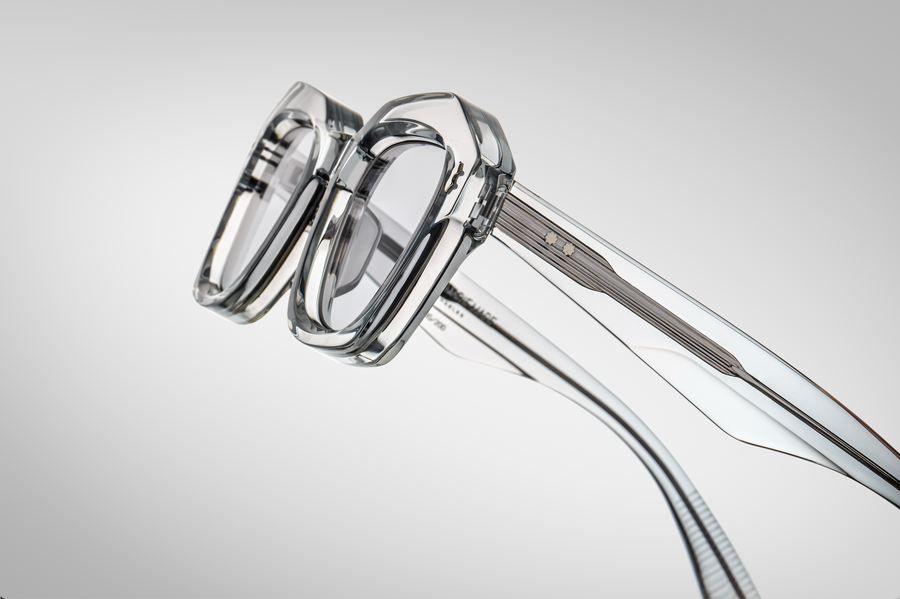 Close up of a profile view of clear sunglasses, with exposed silver hardware on the temples.