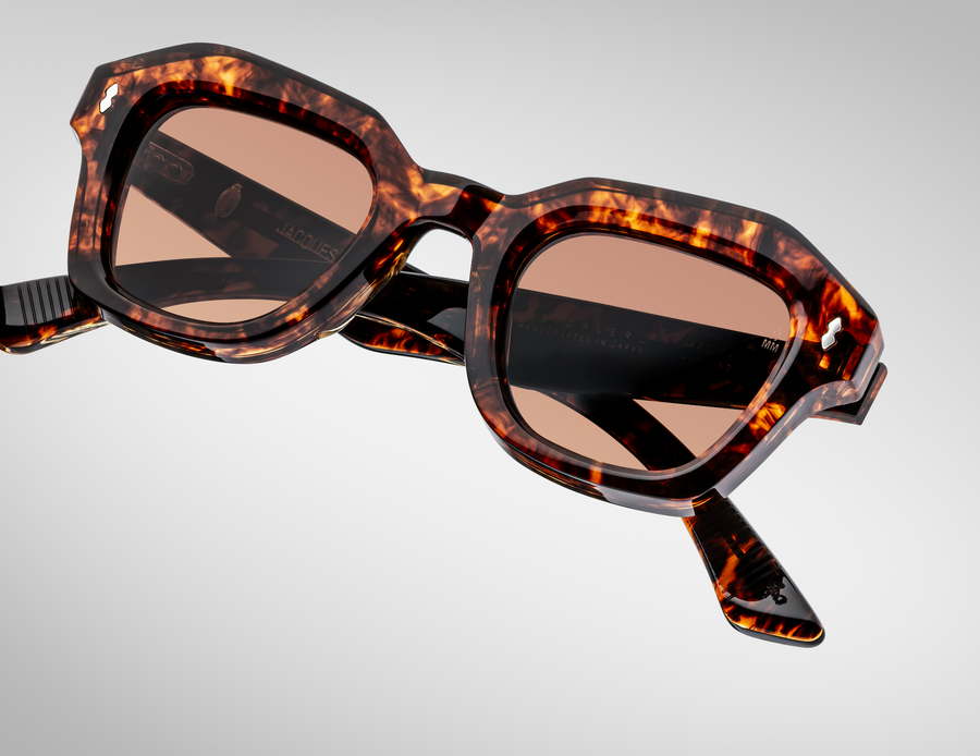 Sunglasses with tortoiseshell frame and brown lenses on a light gray background