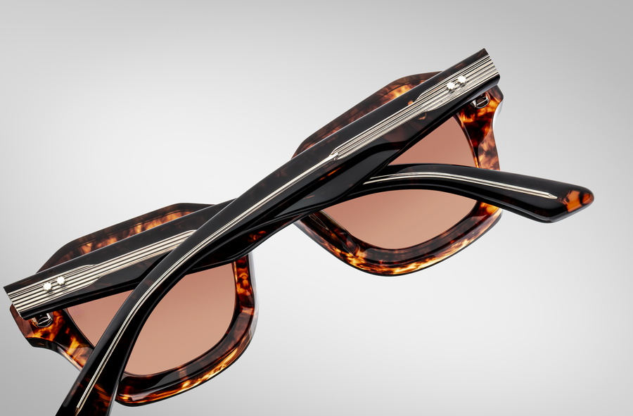 Back view of sunglasses with tortoiseshell frame and brown lenses, with the temples folded across to show the exposed silver hardware.