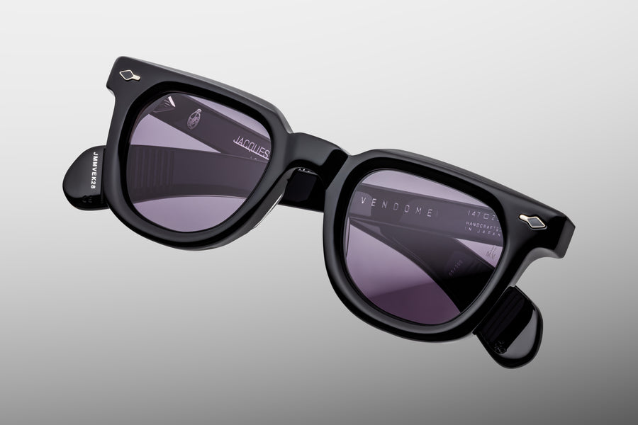 Black sunglasses with reflective purple lenses on a gray background
