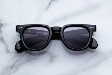 Thick black acetate  panto sunglasses with purple lenses on a white marble background