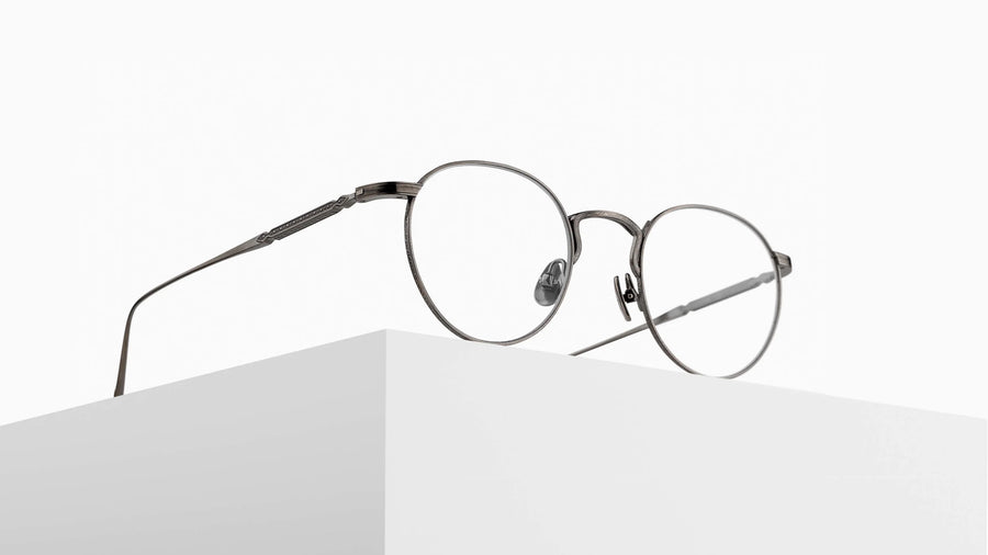 Round silver metal eyeglasses on a white surface with a white background